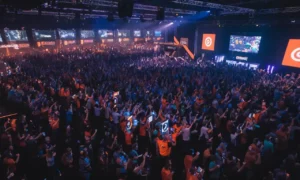 Una multitud animando en el evento de juego de QuakeCon entre pantallas que muestran juegos y logotipos de id Software.